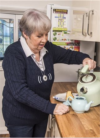 Lady making cup of tea wearing pendant